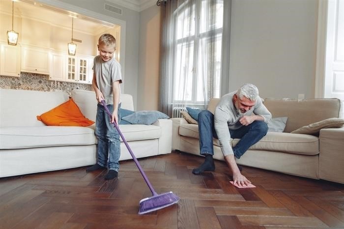 Малыш вместе с отцом занимаются уборкой внутри дома.
