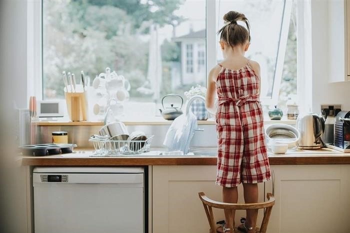 Ребенок занимается моением посуды.