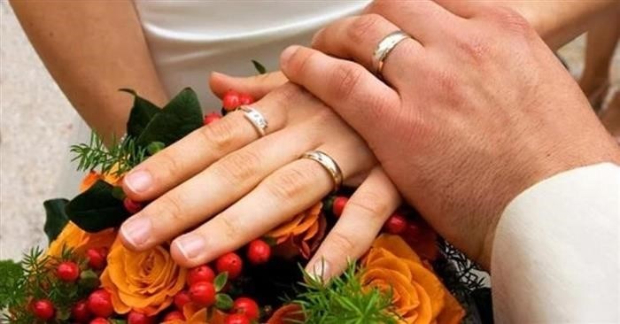 Руки, на которых сверкают обручальные кольца, и букет изящных цветов в руках
