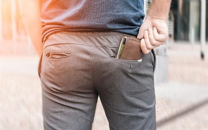 Мужчина извлекает кошелек из своего заднего кармана.