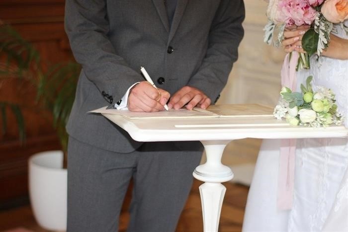 Жених прикладывает свою подпись на документе о заключении брака.